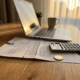 Eiken bureau met Nederlandse belastingaangifte onder laptop, rekenmachine en euromuntstuk in warm middaglicht.