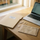 Opgeruimd thuiskantoor met belastingaangifte map, euromunten en officiële envelop naast laptop, warme middagbelichting.