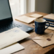 Freelancer bureau met Nederlands belastingdocument onder laptop, gestempelde envelop en koffiekop in warm beige en donkerblauw licht.