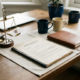 Freelance bureau met arbeidscontract en portfolio naast elkaar, miniweegschaal met pen en officieel document, warm natuurlijk licht.