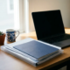 Freelance thuiswerkplek met laptop, transparante documentenmap, koffiemok en succulent in zacht natuurlijk daglicht.
