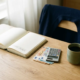 Freelancer bureau met open budgetboekje, eurobiljetten, rekenmachine en koffiekopje in zacht ochtendlicht.