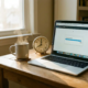 Freelancer bureau met laptop met bijna voltooide voortgangsbalk, analoge klok en dampende koffie in warm ochtendlicht.