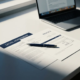 Juridisch contract en factuur naast elkaar op wit bureau met pen, freelancer-laptop onscherp op achtergrond.