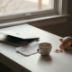 Omgevallen spaarpot op minimalistisch wit bureau met verfrommelde factuur en leeg koffiekopje naast laptop, symbool voor financiële stress als freelancer.