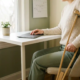 Freelancer met kruk aan bureau, hand op gesloten laptop, kalender en plant op de achtergrond, zacht natuurlijk daglicht.