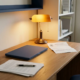 Freelancer aan opgeruimd houten bureau met ongetekend overheidsdocument, laptop en kalender van 2026 in warm amberkleurig lamplight.