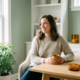 Zelfverzekerde freelancer aan minimalistisch bureau met koffiemok, natuurlijk daglicht en groene plant in modern thuiskantoor.