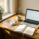 Freelancer thuiskantoor met laptop, dampende koffie, bonnetjes en open notitieboek op houten bureau in warm ochtendlicht.
