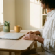 Freelancer aan minimalistisch thuiskantoor bureau met gesloten laptop, koffiemok en succulent in warm middaglicht.
