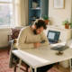 Freelancer aan wit bureau onderzoekt papieren schild naast laptop en muntenstapel in warm ingericht thuiskantoor.