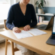 Freelancer aan modern bureau met twee verzekeringsdocumenten naast elkaar, laptop open, thuiskantoor met natuurlijk daglicht.
