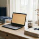 Freelance thuiskantoor met laptop, noodspaarfonds in glazen pot met munten, documenten en verwelkte plant op opgeruimd bureau.