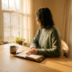 Solo-ondernemer aan een eikenhouten bureau met open dagboek en koud kopje koffie, starend naar een zonnig raam in warm ochtendlicht.