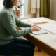 Zelfstandige professional aan een opgeruimd thuiswerkbureau met gesloten laptop, kalender en documenten in zacht natuurlijk licht.