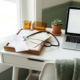 Freelance thuiswerkplek met stethoscoop op stapel medische bonnen en facturen, laptop en succulent op wit bureau.