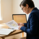 Zelfstandige professional die een verzekeringsdocument bestudeert aan modern bureau met notitieboek, pen en laptop op achtergrond.