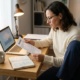 Zelfstandige professional bekijkt verzekeringsDocument aan modern bureau met laptop en notitieboekje met berekeningen.