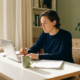 Zelfstandige professional aan wit bureau met laptop en pen boven document, warm middaglicht door raam, thuiskantoor.